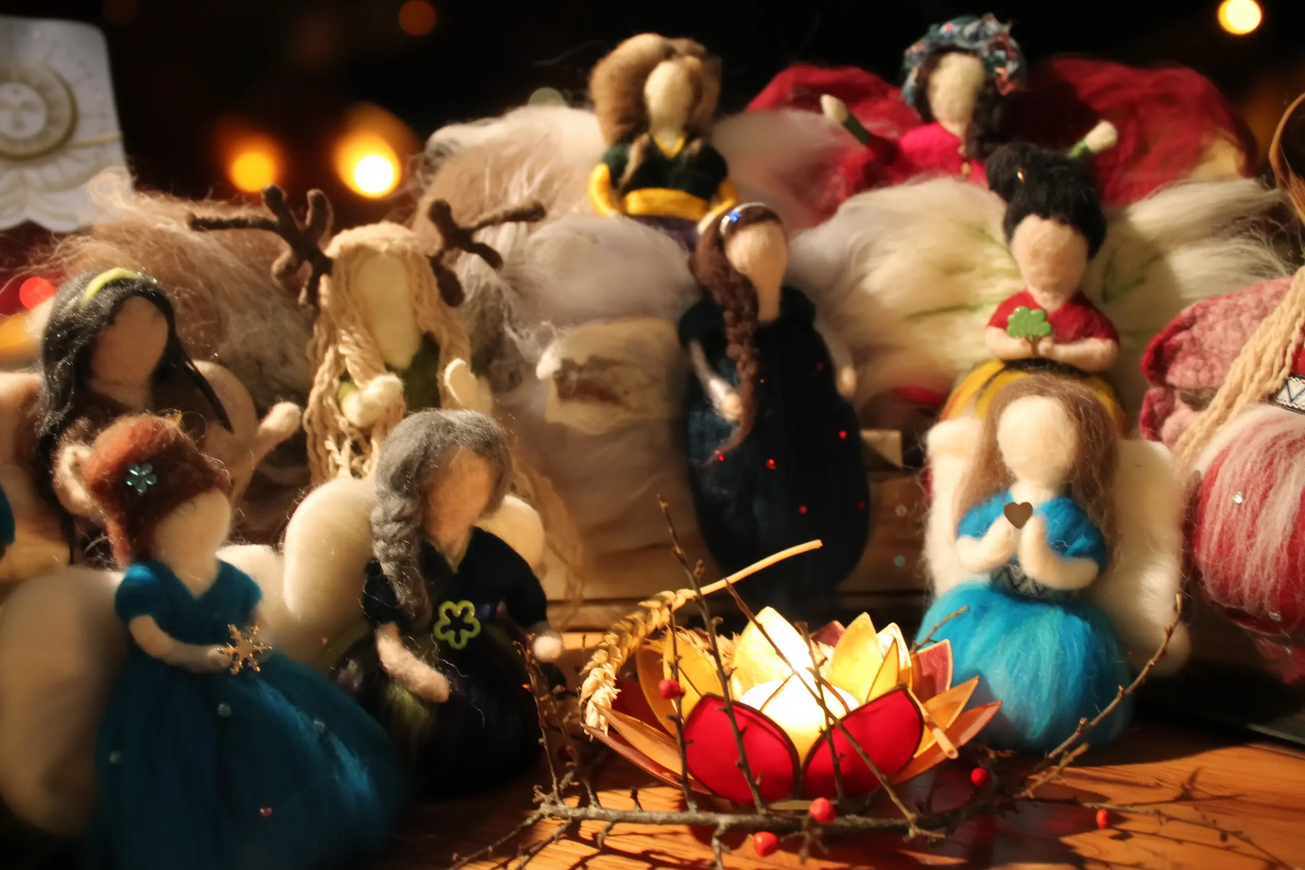 MariaElena | Collection of handmade felted angels in various colors surrounding glowing lotus lantern, showing unique needle felted angel designs by Maria