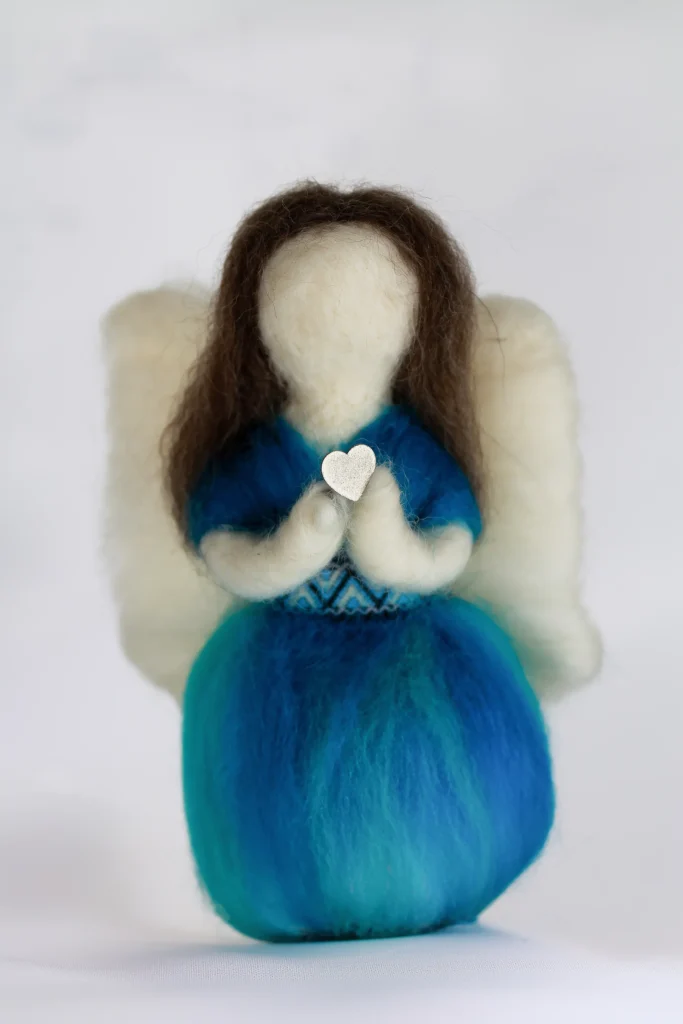 MariaElena | Handmade needle felted angel in ocean blue and teal wool holding white heart at chest with cream wings and dark brown hair