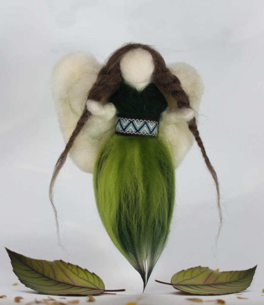 MariaElena | Handmade needle felted guardian angel with long brown braided hair, cream wings, dark green bodice with decorative patterned belt, and bright green flowing dress, standing among autumn leaves and acorns