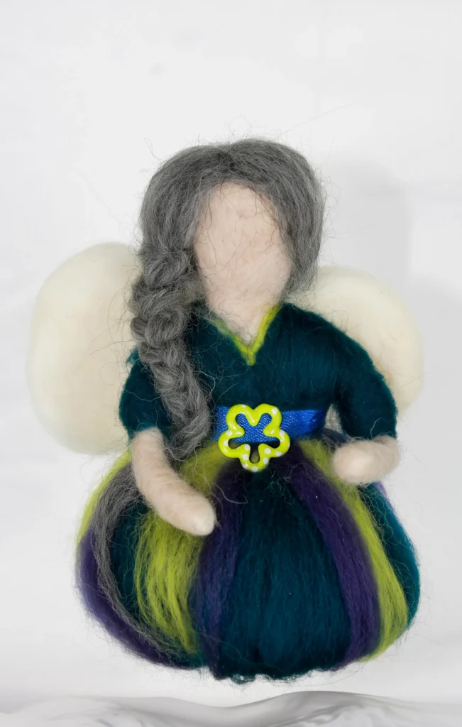 MariaElena | Handmade needle felted guardian angel with long grey braided hair, cream wings, and rich teal dress accented with purple and lime green. A golden key with blue ribbon rests at her chest.